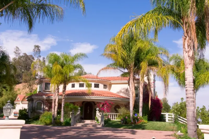 Luxury vacation rental with palm trees, Mediterranean-style architecture, and landscaped gardens in a quiet Cypress neighborhood.