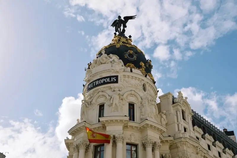 Metropolis Building dome with winged statue and Spanish flag on Gran Via, iconic Madrid landmark