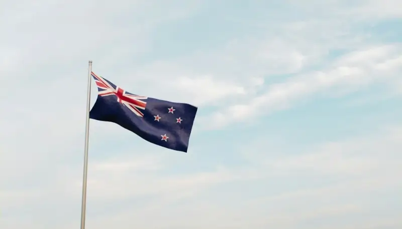 New Zealand flag with Union Jack and Southern Cross stars waving against blue sky