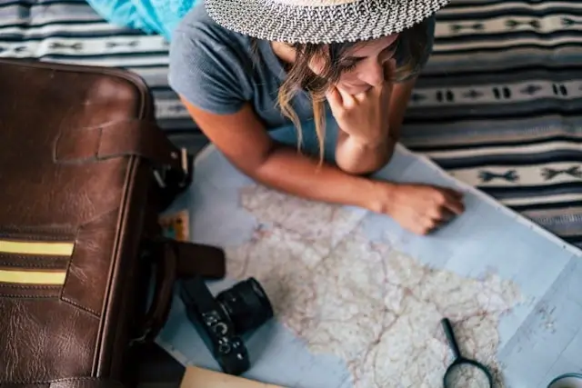 Traveler studying paper map with camera and luggage planning efficient route through destination