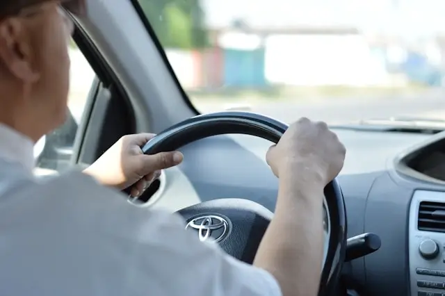 Professional driver in white shirt steering Toyota vehicle during private transfer service