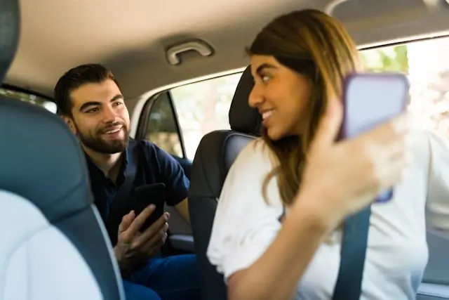Passengers using rideshare service checking smartphone app during safe convenient city transportation