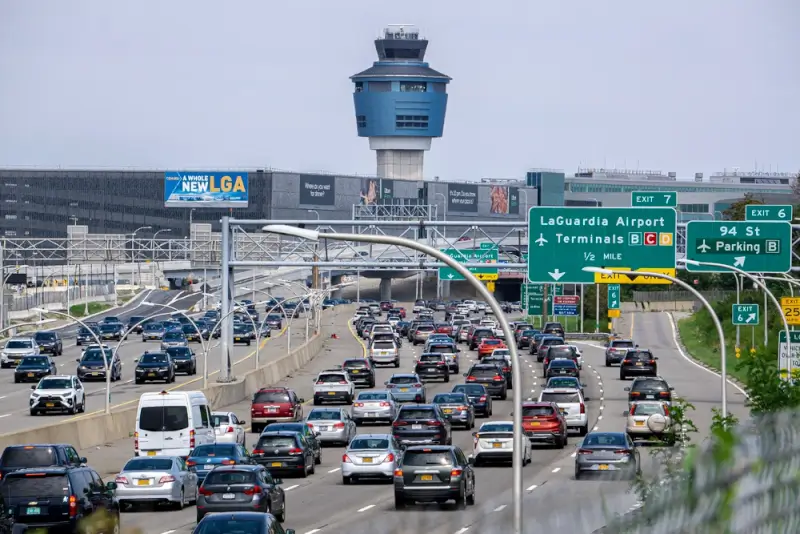 "Heavy traffic on highway approaching LaGuardia Airport terminals with control tower visible in New York