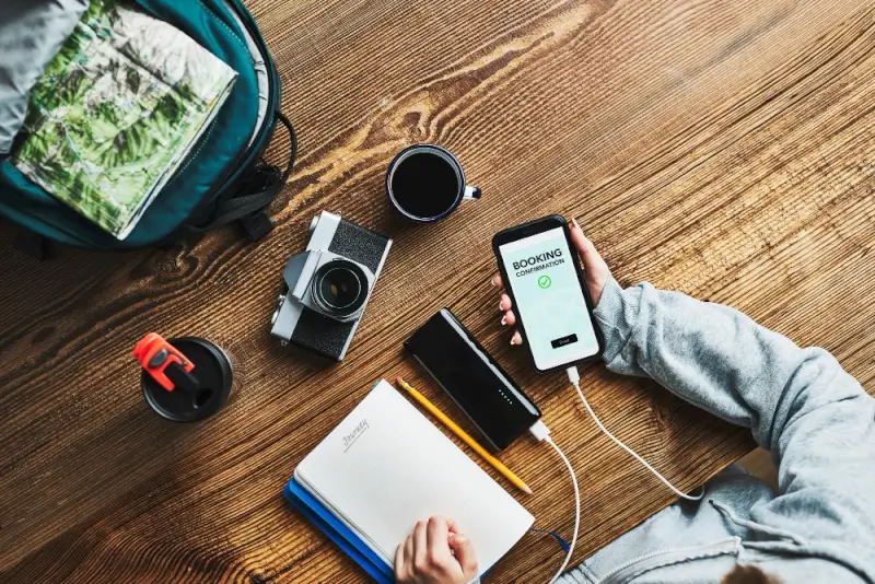 Travel planning setup with camera, notebook, and phone for creating podcast episodes from video content