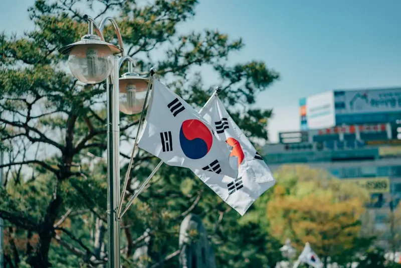 South Korean flag waving on street pole with urban cityscape and trees in background