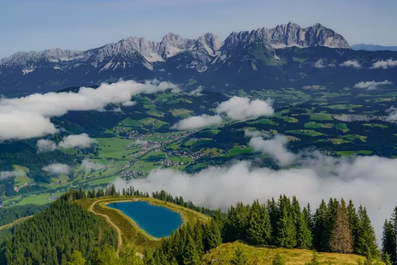 Wilder Kaiser mountain range with Ellmauer Halt peak rising above morning clouds and alpine lake in the eastern Adlerweg section