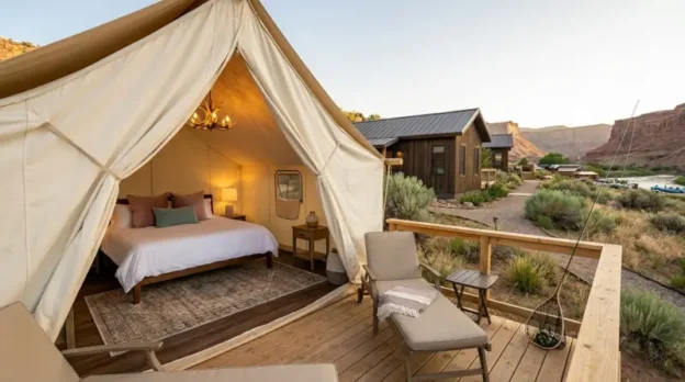 Upscale canvas tent with plush bedding and private deck overlooking red rock canyon landscape