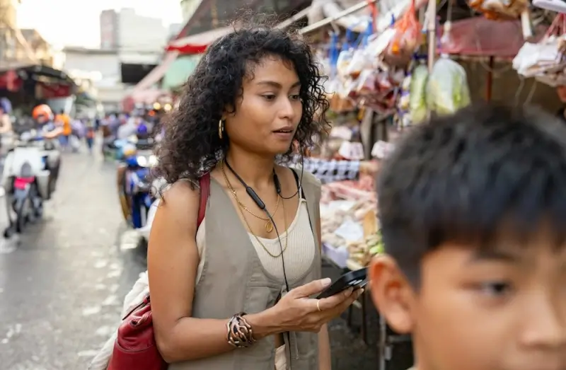 Woman using mobile phone with local eSIM in Indonesia traditional market