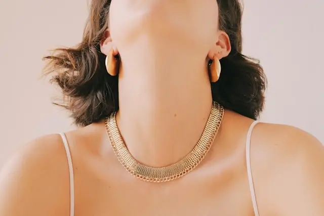 Woman wearing gold statement hoop earrings and layered chain necklace for evening accessory transition