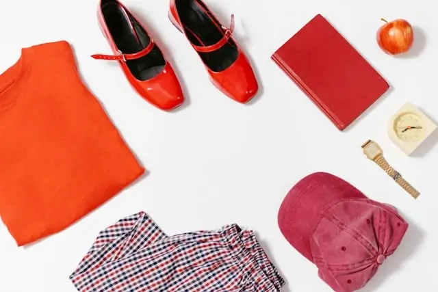 Flatlay of red mary jane flats with orange skirt, plaid shirt, burgundy cap, and accessories for day to night styling