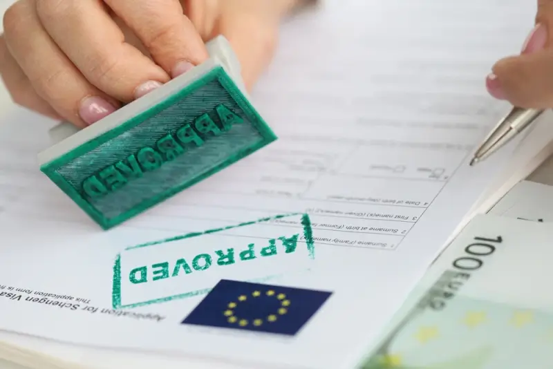 Hand stamping approved on European visa application documents with EU flag for successful relocation process