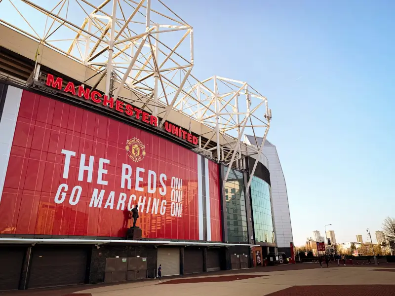 Old Trafford stadium exterior with Manchester United signage and iconic red facade in Manchester England