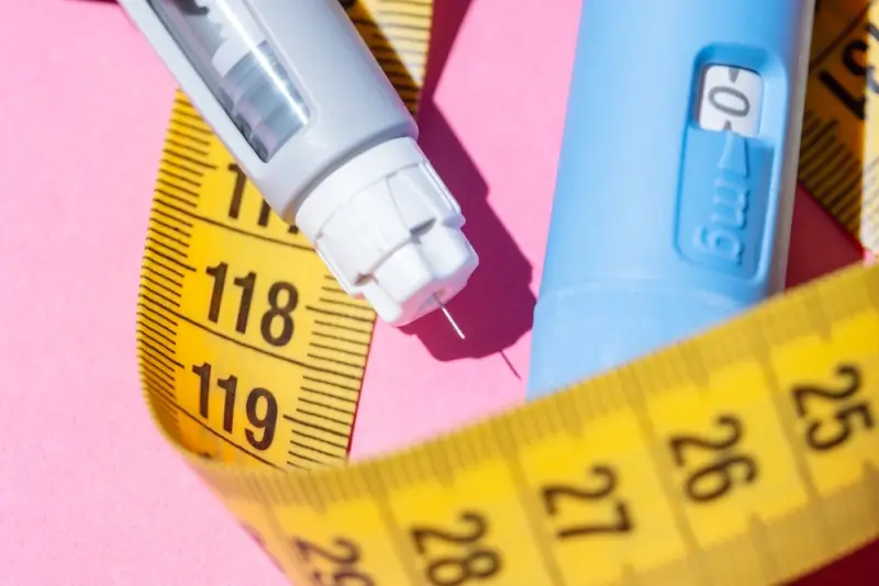 Semaglutide injection pen with measuring tape representing weight loss progress and body measurements