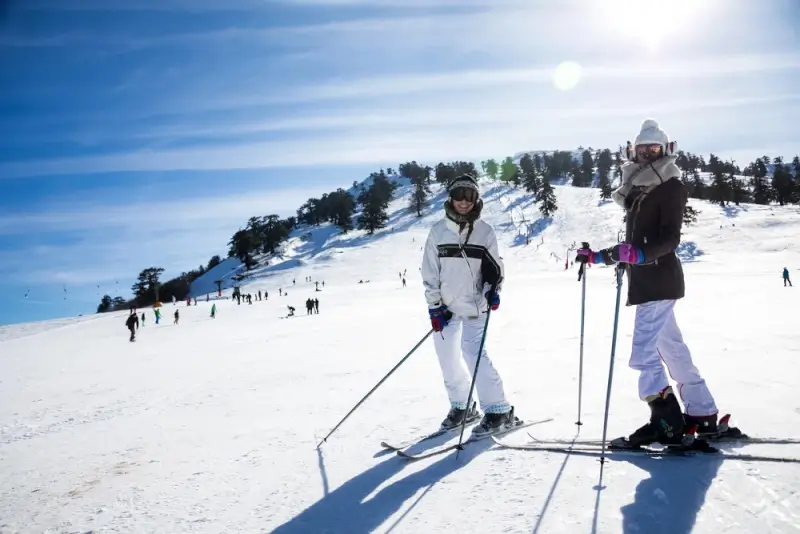 Two skiers posing on sunny slopes at Vasilitsa Ski Resort in the Pindus Mountains of Greece
