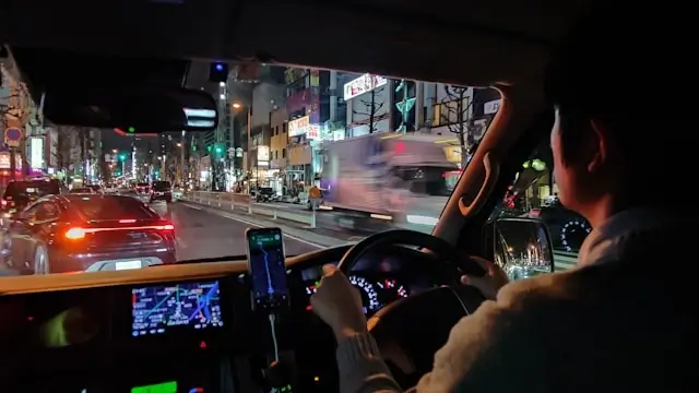 Reckless rideshare driver using smartphone while speeding through busy city street at night