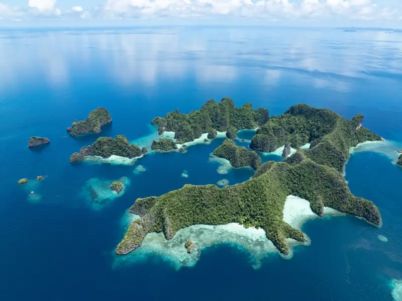 Aerial view of rugged limestone karst islands in Misool, southern Raja Ampat, surrounded by shallow reefs and deep channels popular with safari boats