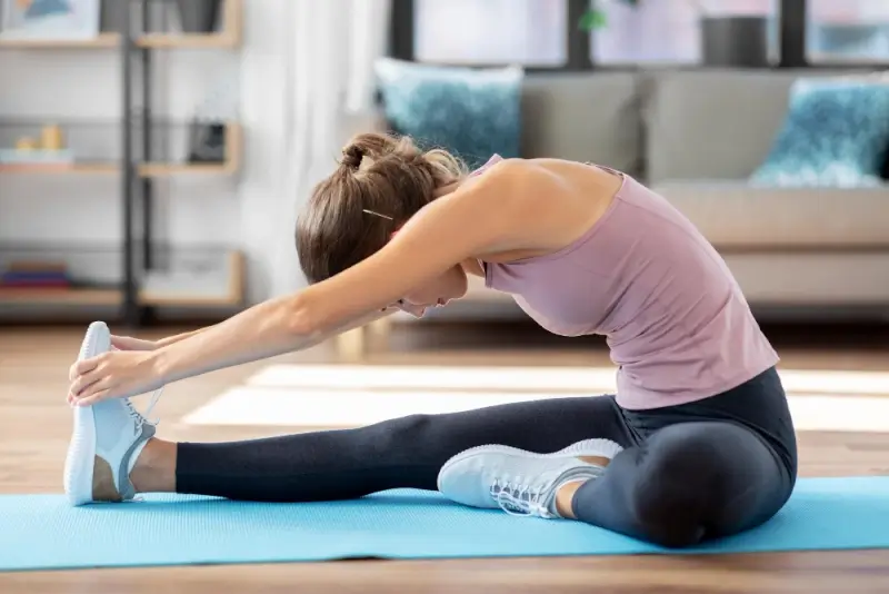 Woman stretching on yoga mat at home in cozy living room during morning routine
