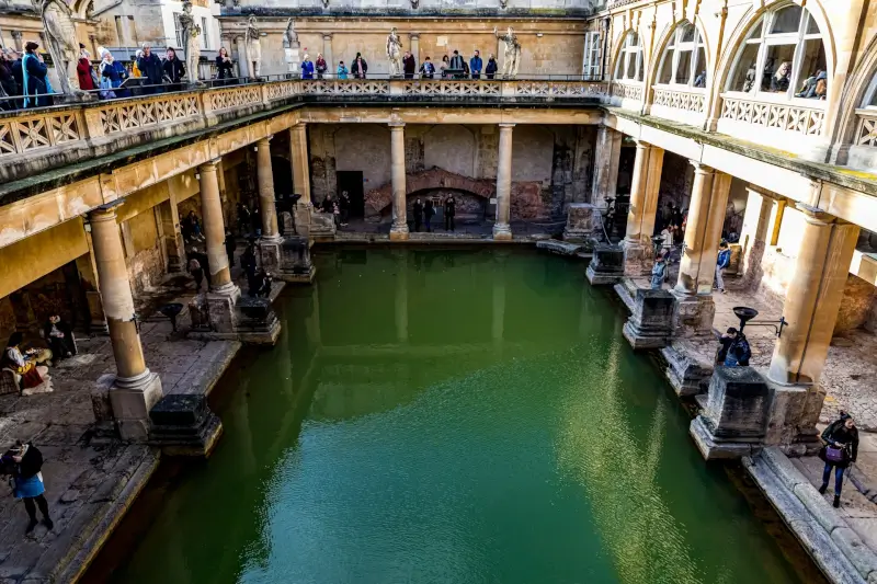 Ancient Roman Baths with green thermal water and stone columns in Bath England UNESCO World Heritage site