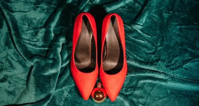 Red ballet flats with gold earrings displayed on emerald green velvet fabric for versatile outfit styling
