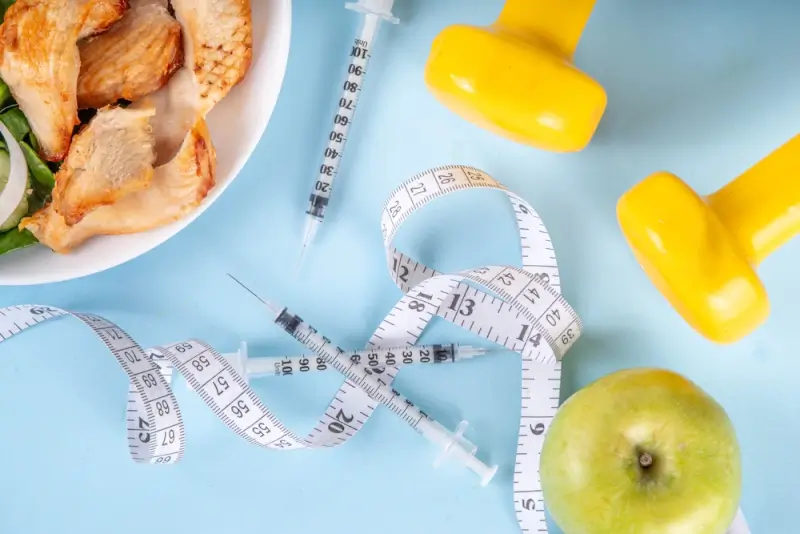 Weight loss treatment plan with injection pens, healthy food, measuring tape, and exercise equipment