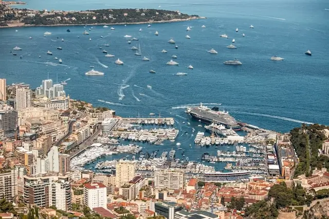 Aerial view of Monaco's Port Hercules filled with luxury yachts and superyachts anchored in turquoise Mediterranean waters during the Monaco Yacht Show