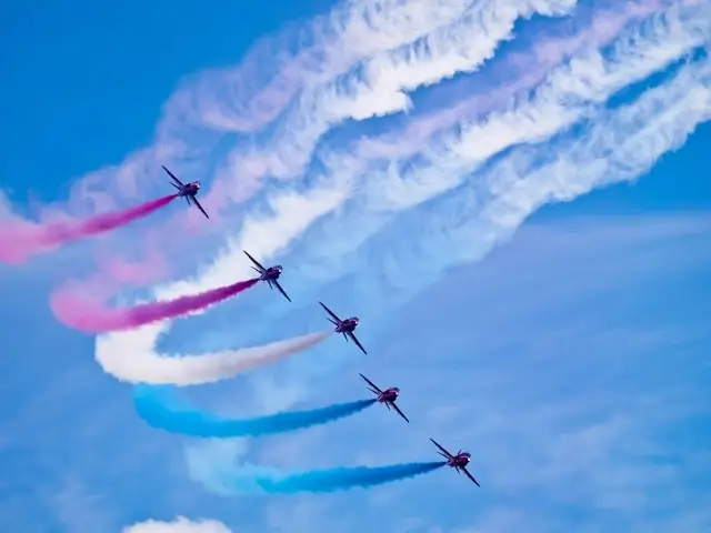 Aerobatic jets performing synchronized formation flight with colorful smoke trails at first air show