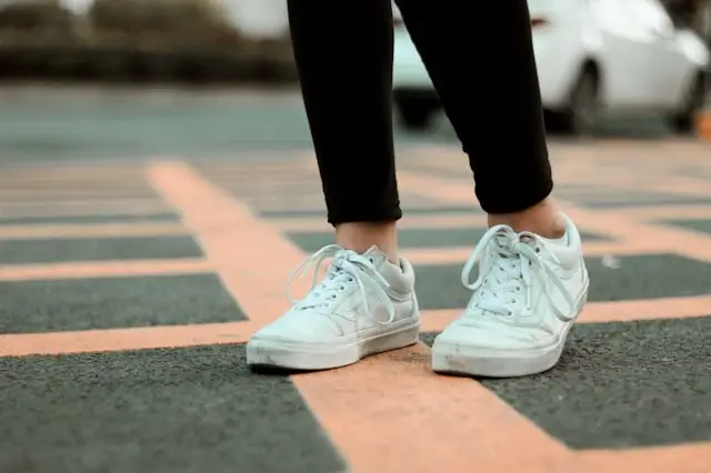 Woman wearing white sneakers for walking tours standing on a striped urban street