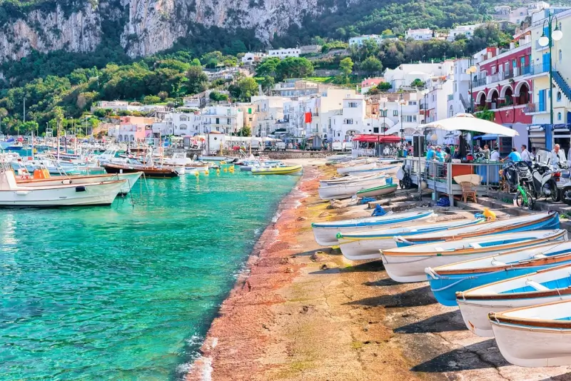 Marina Grande harbor with colorful boats lined along the shore and white buildings nestled against limestone cliffs