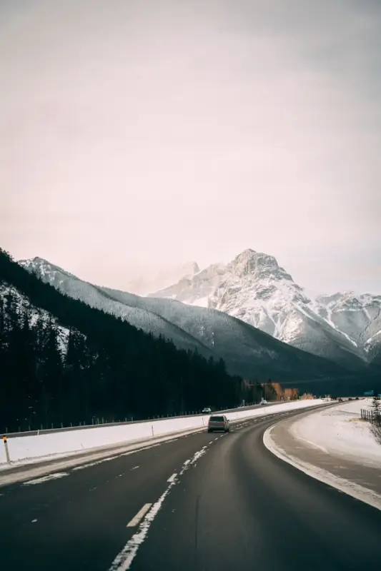 Winding mountain highway with vehicle traveling through Canadian Rockies in winter