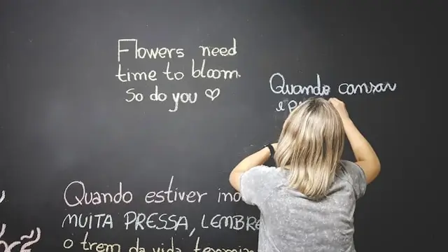 Student writing foreign language phrases on a blackboard during a language class