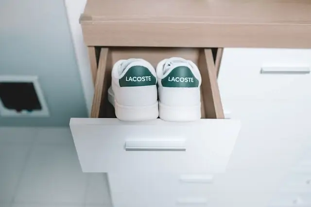 White Lacoste leather sneakers stored in an open dresser drawer