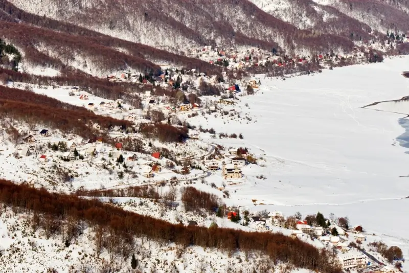 Mavrovo National Park winter landscape with frozen lake and mountain village in North Macedonia
