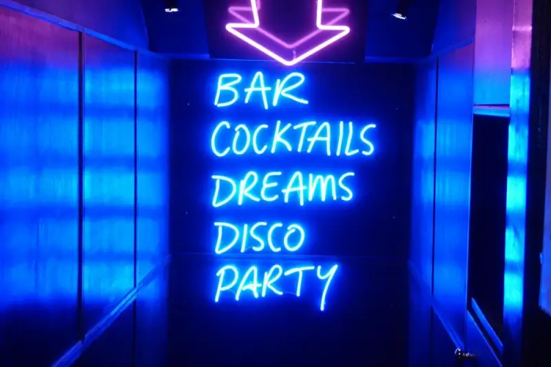 Neon sign displaying bar cocktails dreams disco party at nightclub entrance in London