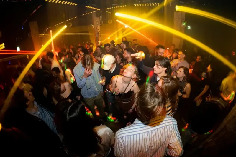 Crowded dance floor with yellow light beams and partygoers enjoying club atmosphere