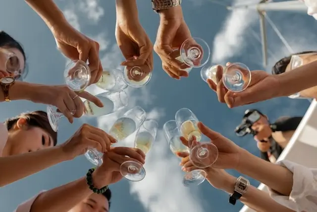 Friends toasting with champagne glasses at pre-wedding party on luxury yacht