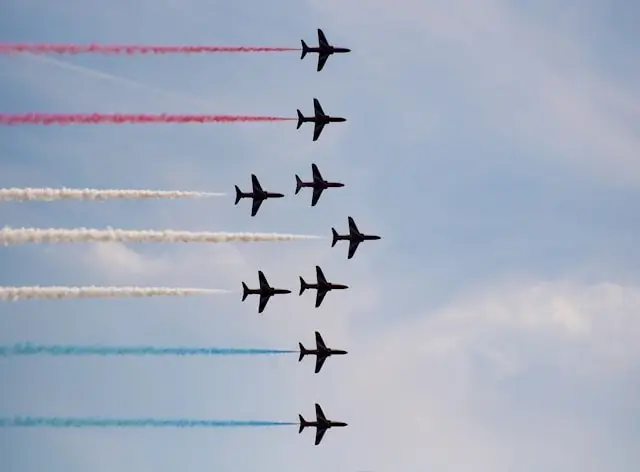 Military jets performing diagonal formation display with red white and blue smoke trails