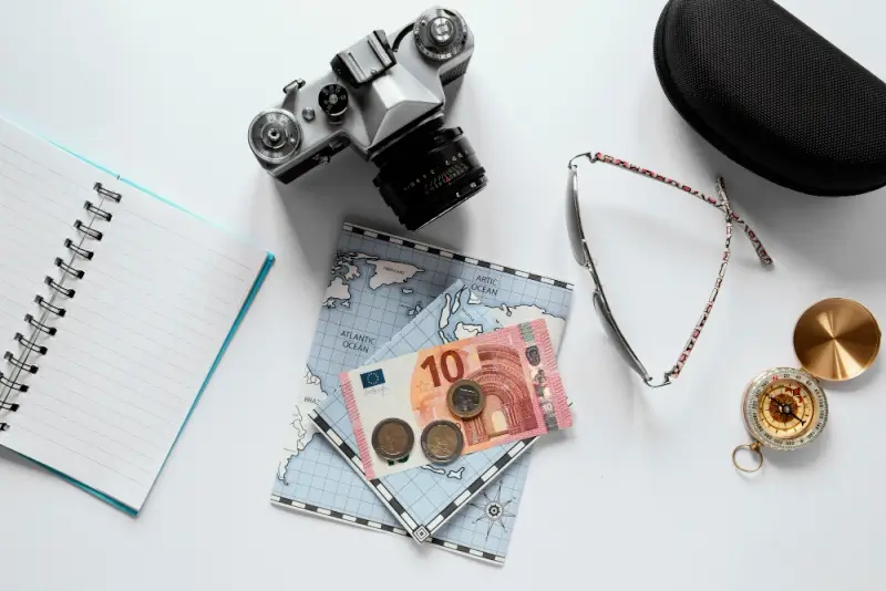Travel budget planning with euro currency, notebook, camera, compass, and map on white background