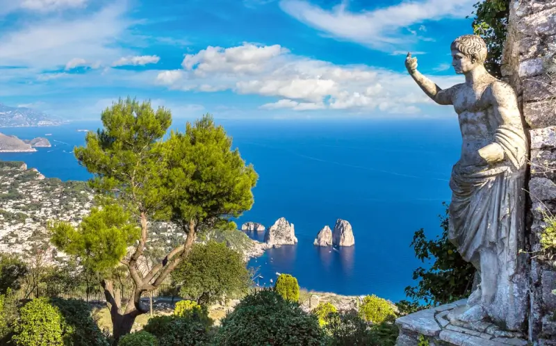 Classical statue overlooking the famous Faraglioni rock formations rising from the turquoise sea off the coast of Capri