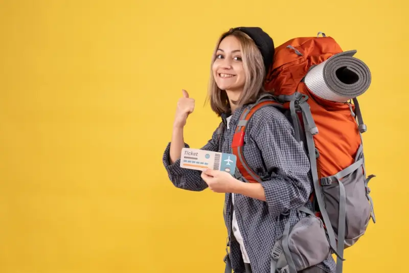 Happy backpacker holding confirmed flight ticket with orange backpack ready for travel adventure