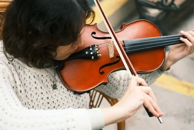 A woman playing a violin with a bow, a helpful visual for a violin guide for beginners