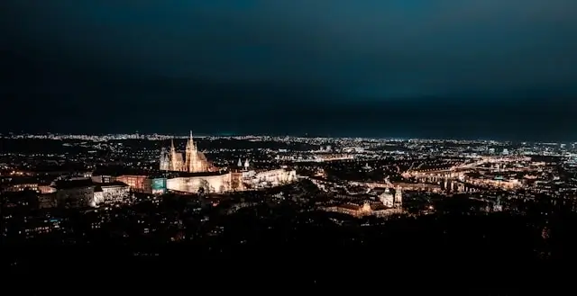 Aerial view of Prague at night with the illuminated castle and city lights spreading across the skyline