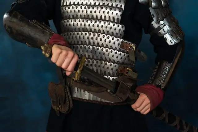 Close-up of a buhurt armor guide showing layered steel plates and a belted weapon