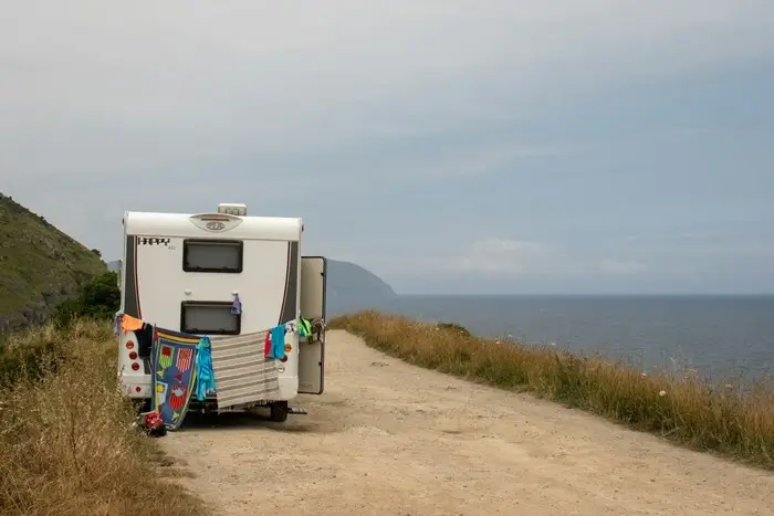 campervan parked on a coastal dirt road with towels hanging on the door and sweeping ocean views