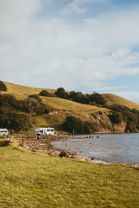 campervan rental guide to New Zealand with an RV parked by a scenic coastal hillside