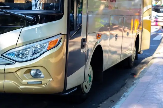 A gold coach bus parked along a city street, representing commercial passenger transport services and their legal duty of care obligations