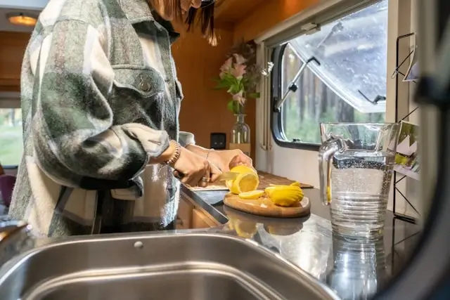 person slicing lemons on a cutting board in a compact campervan kitchen