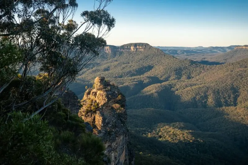 Breathtaking view from Echo Point in Katoomba, with dramatic sandstone rock formations, lush green valleys, and rolling Blue Mountains ranges stretching into the horizon — a perfect reason to explore New South Wales during shoulder season.