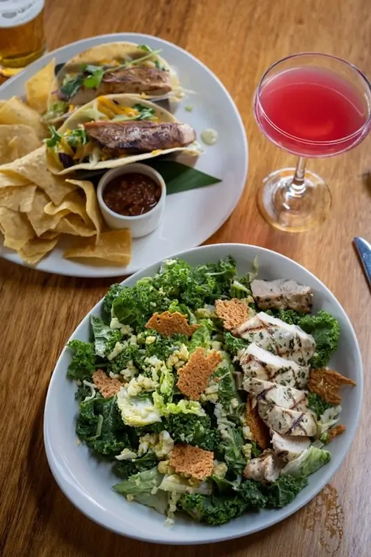 casual Maui dining spread with fresh fish tacos, chips, a grilled salad, and tropical cocktails for couples