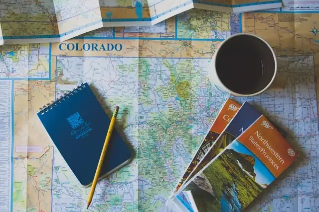 travel logistics for group travel flat lay with maps, notebook, and coffee cup