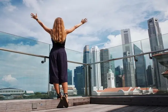 Solo female traveler enjoying a stress-free moment on a rooftop terrace with a city skyline view showing how to minimize travel stress